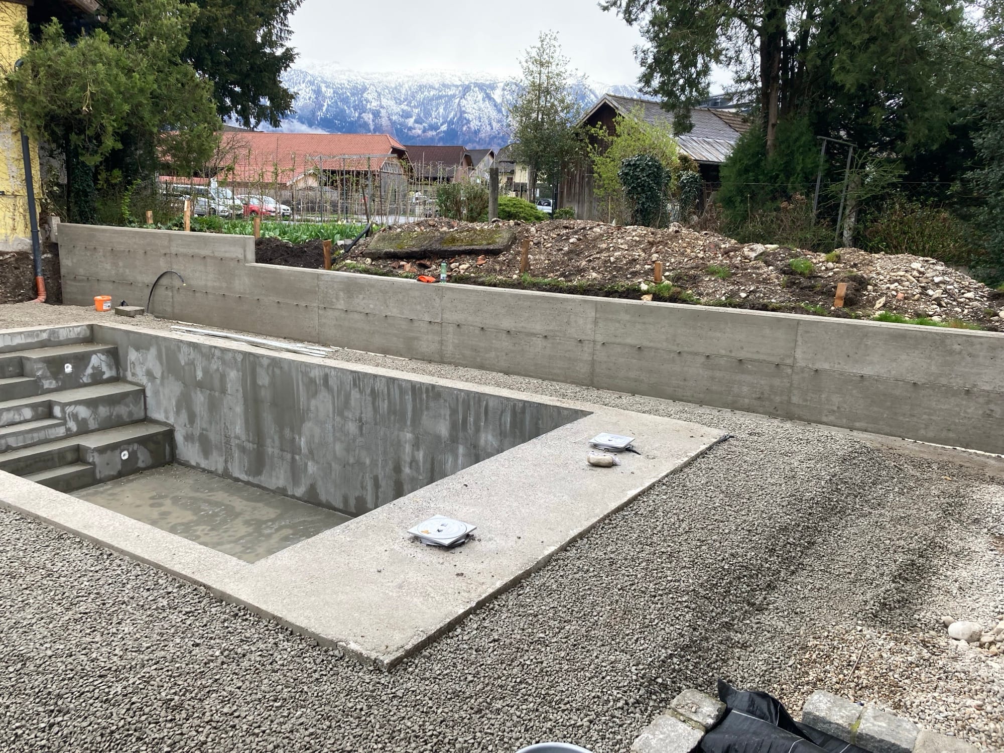 Betonierte Poolwanne, dahinter die Berge