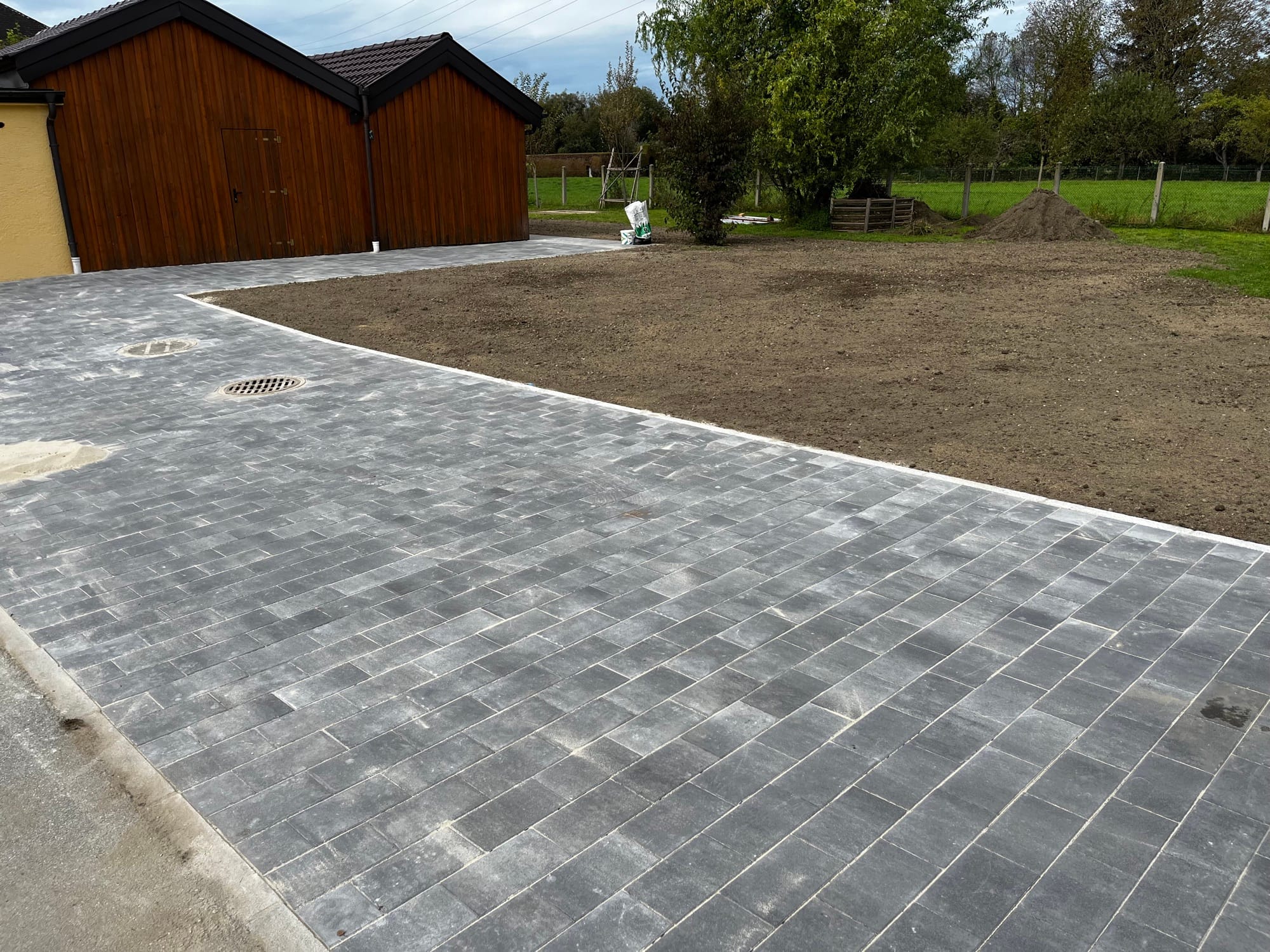 Gepflasterte Einfahrt vor einem Holzcarport