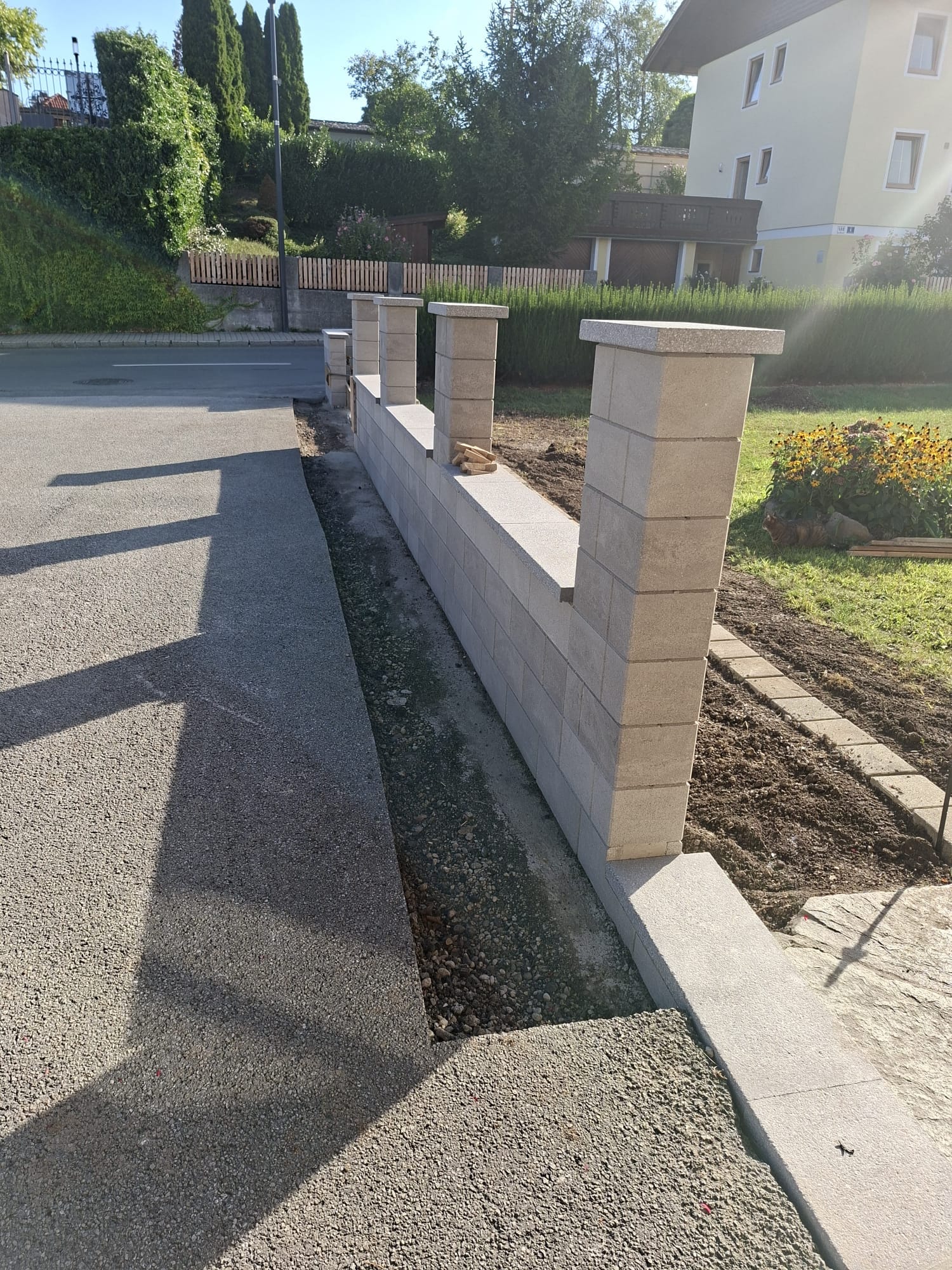 Gartenmauer mit Steinpfeilern und angrenzendem Plattenweg