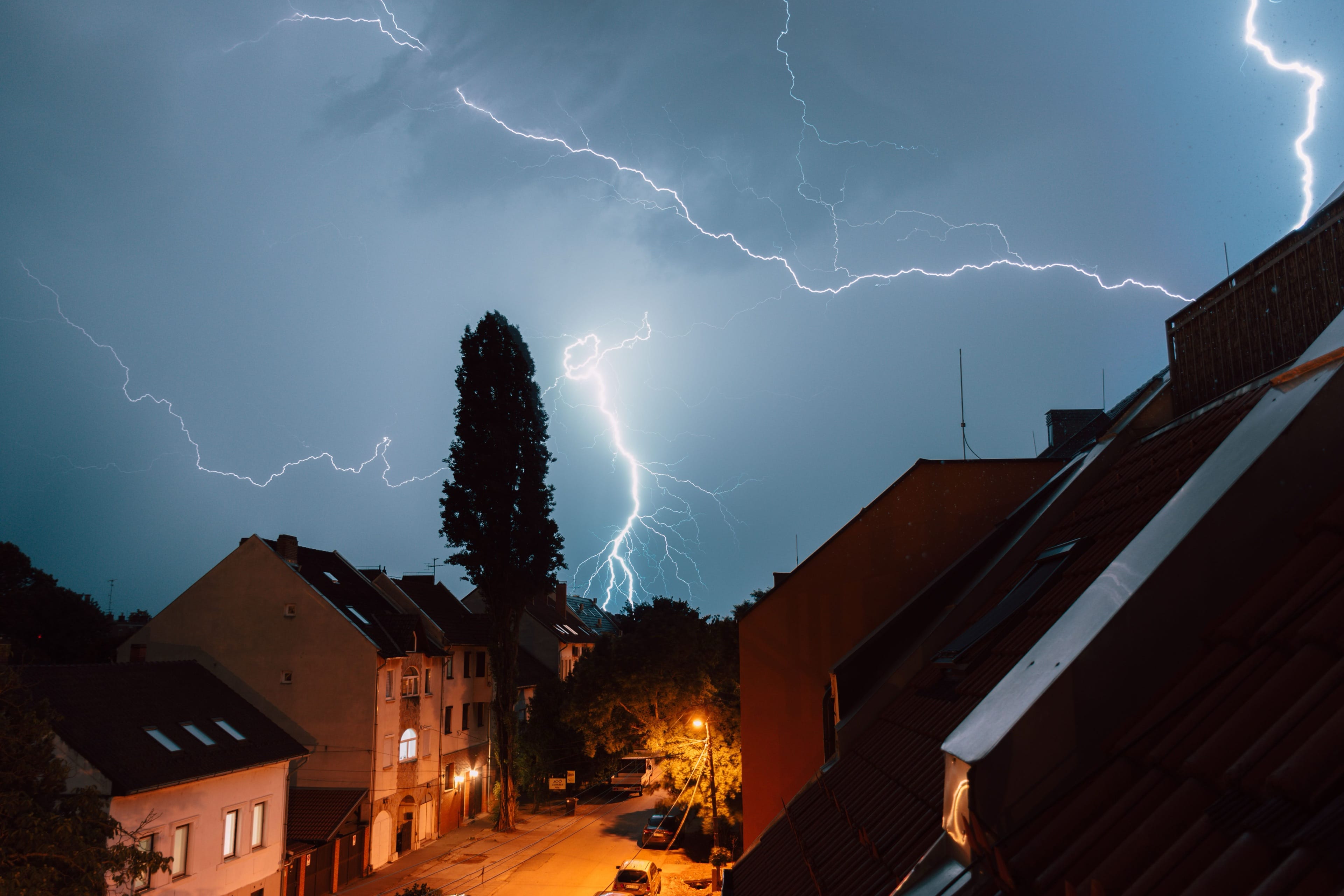 Gewitter mit Blitzen über den Dächern eines Wohngebiets