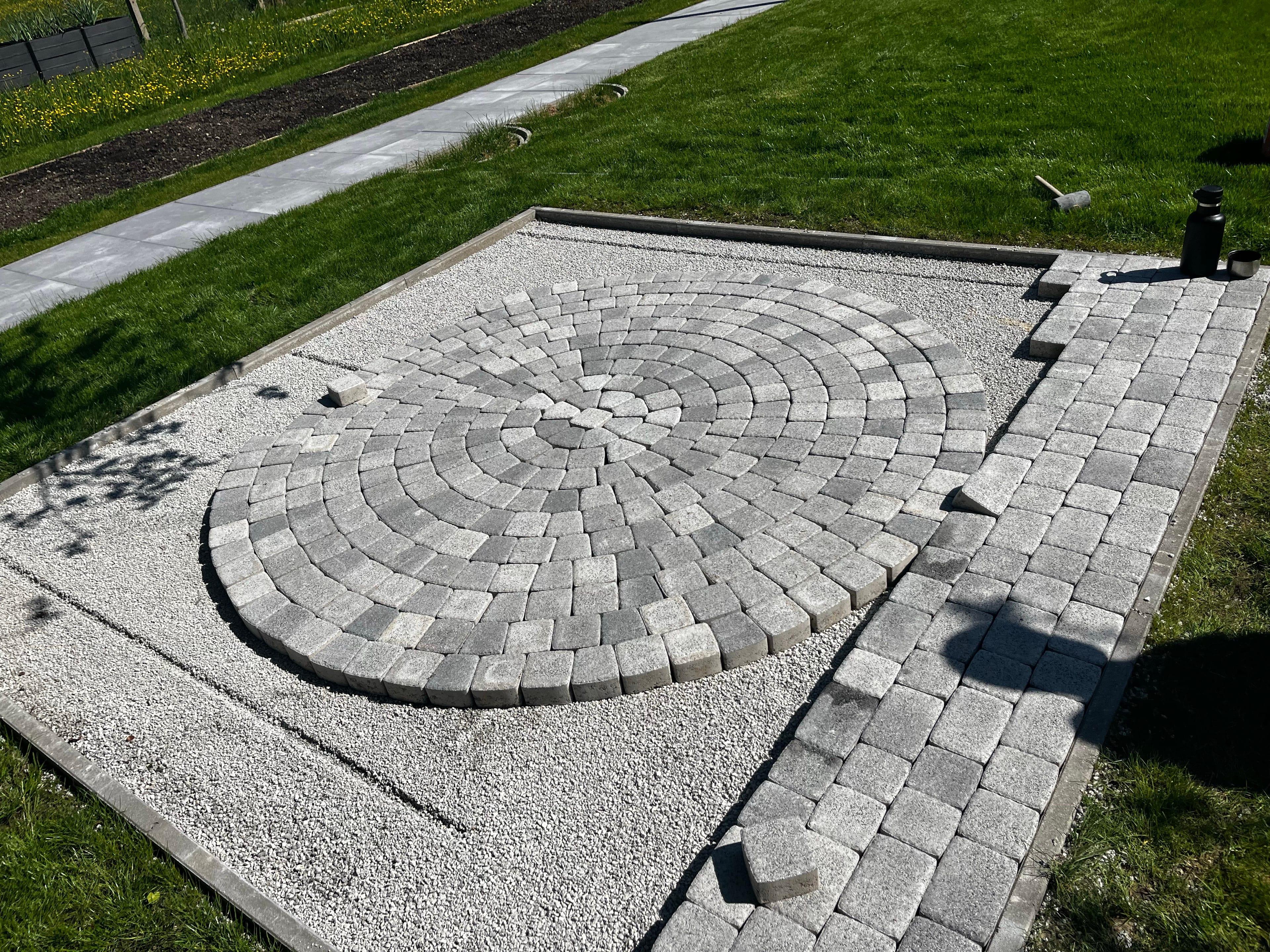 Gepflasterter Platz mit kreisförmig verlegten Steinen im Garten